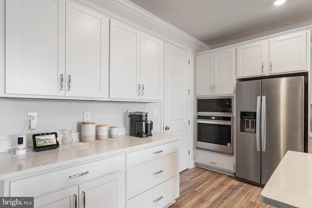 kitchen with crown molding, white cabinets, and appliances with stainless steel finishes