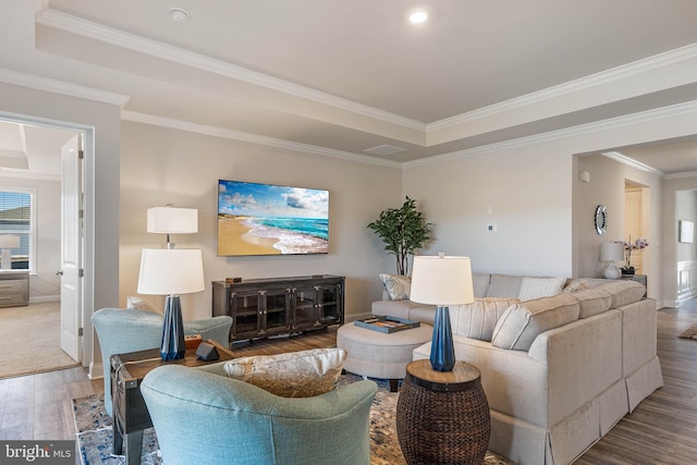 living room featuring a raised ceiling, ornamental molding, and hardwood / wood-style floors