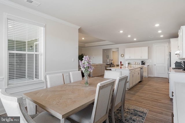 dining room with ornamental molding and light wood-type flooring