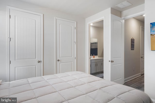 bedroom with ensuite bathroom and hardwood / wood-style floors