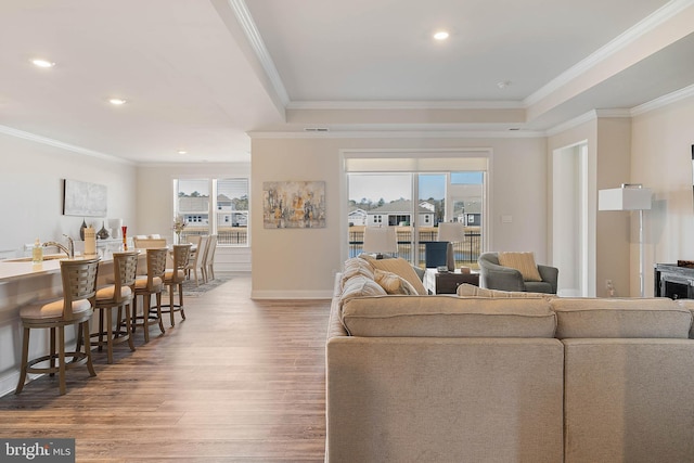 living room with crown molding, plenty of natural light, sink, and hardwood / wood-style floors