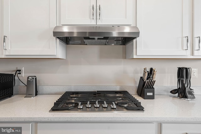 room details featuring white cabinetry, extractor fan, light stone counters, and stainless steel gas stovetop