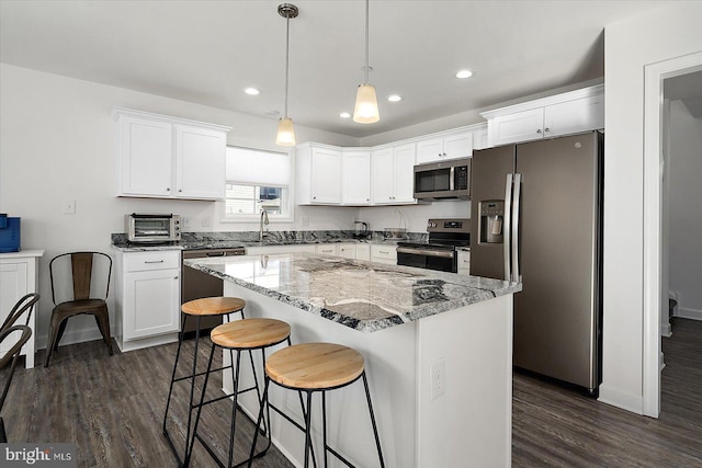 kitchen with sink, white cabinetry, a kitchen island, pendant lighting, and stainless steel appliances