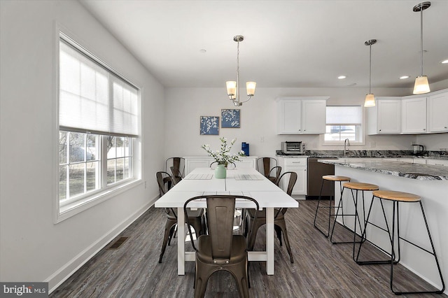 dining room with sink, an inviting chandelier, and dark hardwood / wood-style flooring