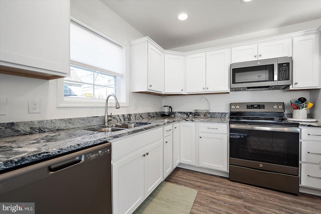 kitchen featuring stainless steel appliances, white cabinetry, sink, and dark stone counters