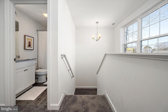 stairs with hardwood / wood-style flooring and a notable chandelier