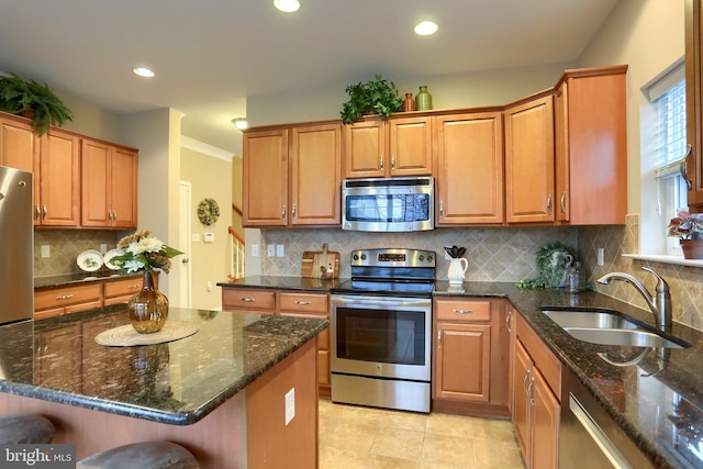 kitchen featuring sink, dark stone countertops, a kitchen breakfast bar, a kitchen island, and stainless steel appliances