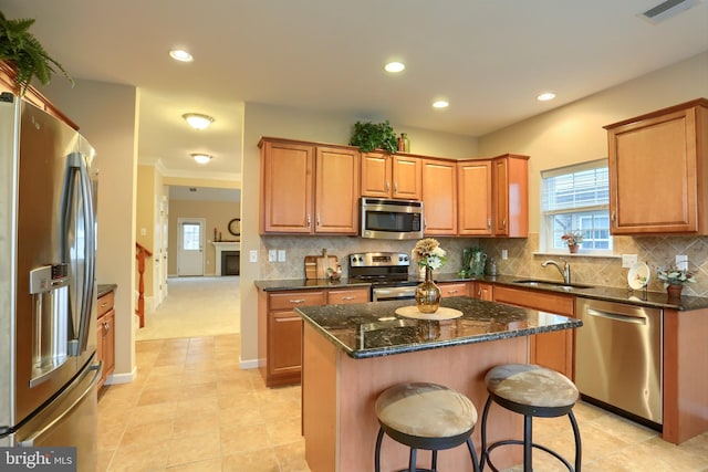 kitchen with a kitchen island, appliances with stainless steel finishes, tasteful backsplash, sink, and dark stone countertops