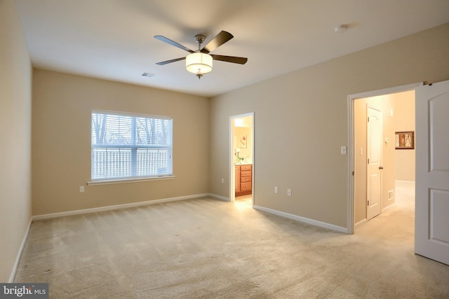 unfurnished bedroom with ceiling fan, light colored carpet, and connected bathroom