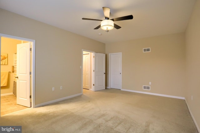 unfurnished bedroom featuring ensuite bathroom, light carpet, and ceiling fan