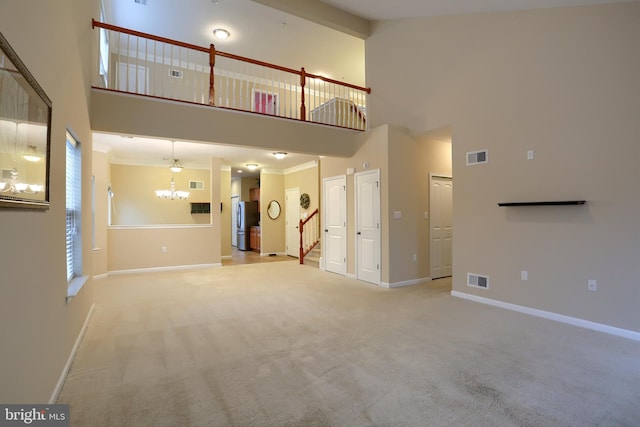 unfurnished living room with an inviting chandelier, light carpet, and a high ceiling