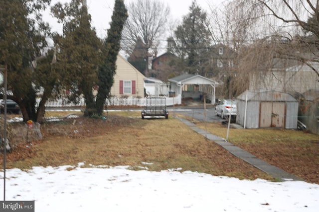 yard layered in snow with a carport and a storage unit