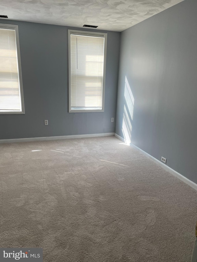 empty room with light colored carpet and a textured ceiling