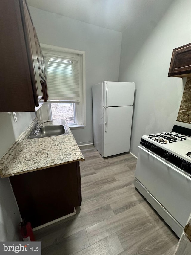 kitchen featuring sink, white appliances, dark brown cabinets, and light hardwood / wood-style floors