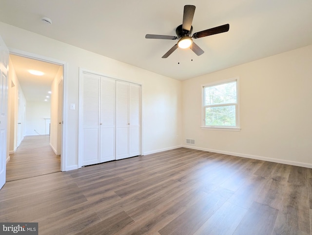 unfurnished bedroom with hardwood / wood-style flooring, ceiling fan, and a closet