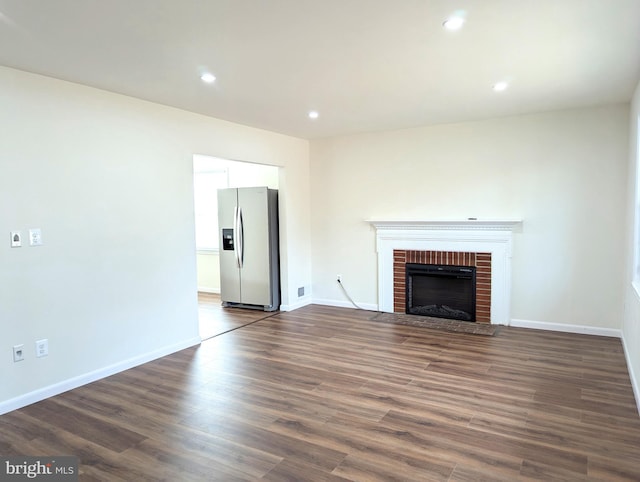 unfurnished living room featuring dark wood-type flooring and a fireplace