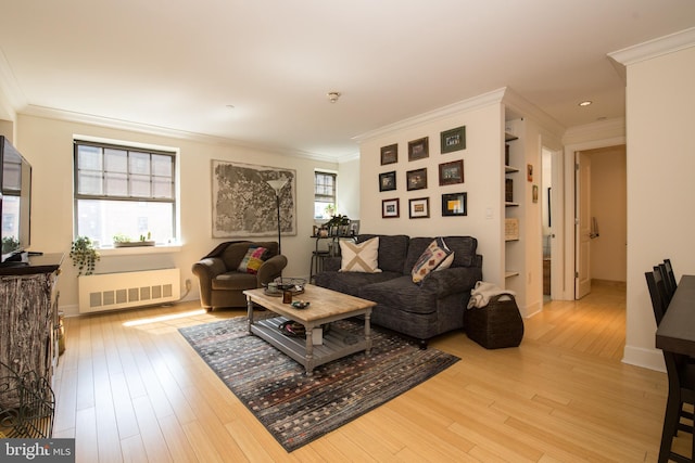 living room featuring light hardwood / wood-style flooring, radiator heating unit, ornamental molding, and a healthy amount of sunlight