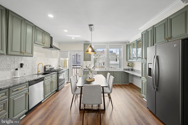 kitchen with stainless steel appliances, light stone countertops, sink, and green cabinets