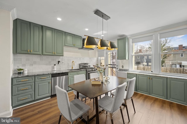 kitchen with appliances with stainless steel finishes, dark hardwood / wood-style floors, decorative light fixtures, sink, and green cabinets