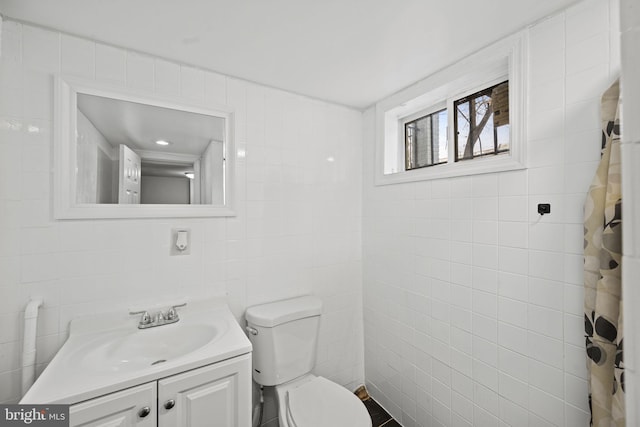 bathroom featuring vanity, toilet, and tile walls