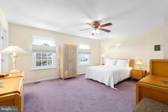 carpeted bedroom with a ceiling fan, multiple windows, visible vents, and baseboards