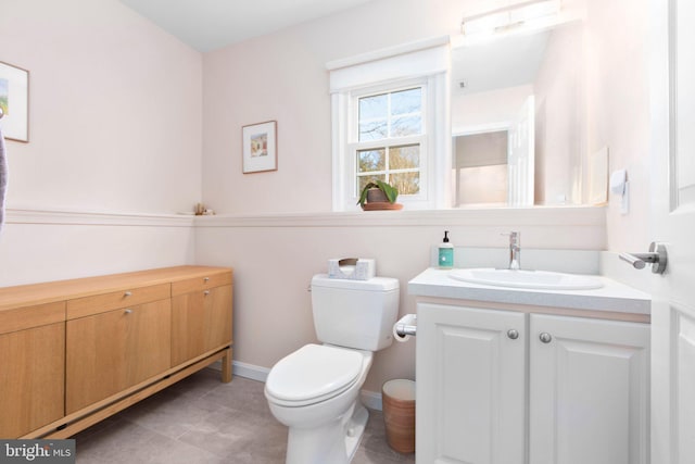 bathroom with toilet, tile patterned floors, baseboards, and vanity