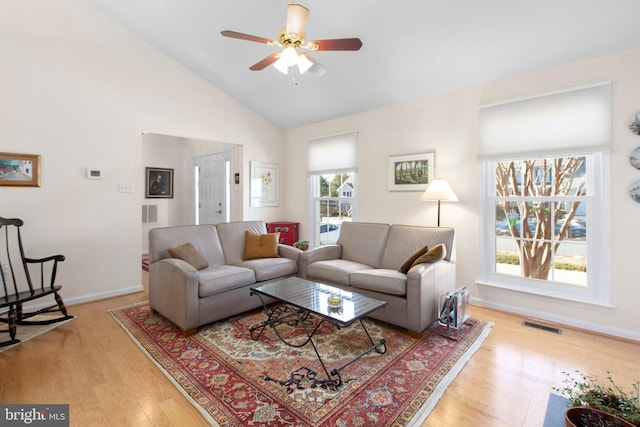 living room featuring high vaulted ceiling, a ceiling fan, visible vents, baseboards, and light wood-type flooring