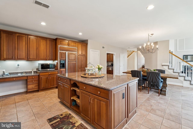 kitchen featuring light tile patterned flooring, decorative light fixtures, paneled refrigerator, a kitchen island, and stone counters