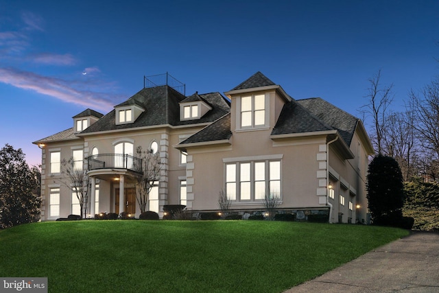 view of front of property with a lawn and a balcony