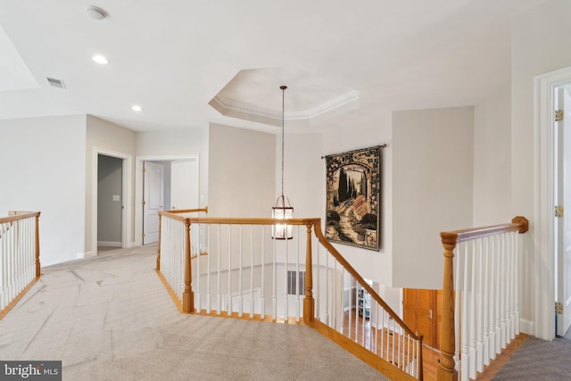 hall with light carpet and a tray ceiling