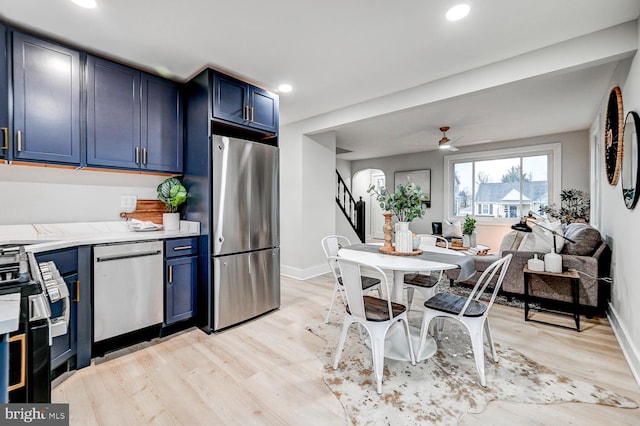 kitchen with stainless steel appliances, light hardwood / wood-style floors, and blue cabinetry