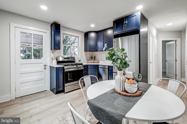 kitchen with blue cabinetry, appliances with stainless steel finishes, and light hardwood / wood-style floors