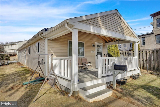 back of property featuring a lawn and covered porch