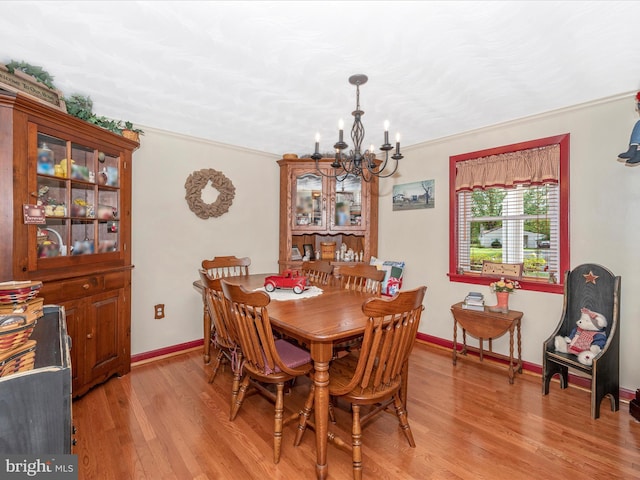 dining area featuring ornamental molding, an inviting chandelier, and light wood-type flooring