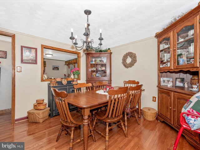 dining area with an inviting chandelier, crown molding, a textured ceiling, and light wood-type flooring