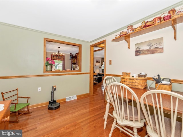 dining space featuring hardwood / wood-style flooring, crown molding, and a chandelier