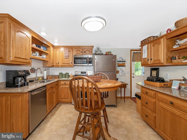 kitchen featuring sink, decorative backsplash, light stone countertops, and appliances with stainless steel finishes