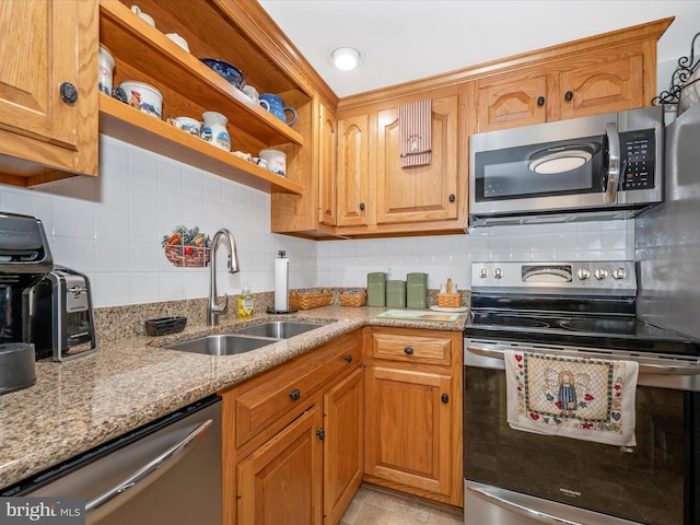 kitchen featuring light stone counters, stainless steel appliances, sink, and decorative backsplash