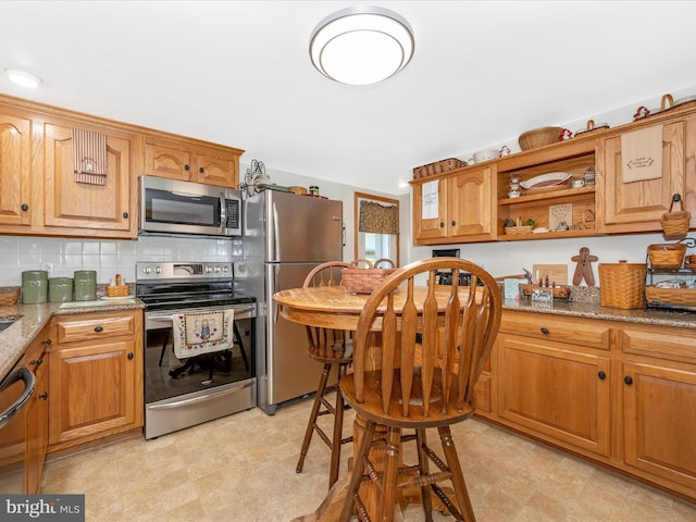 kitchen featuring stainless steel appliances, light stone countertops, and backsplash