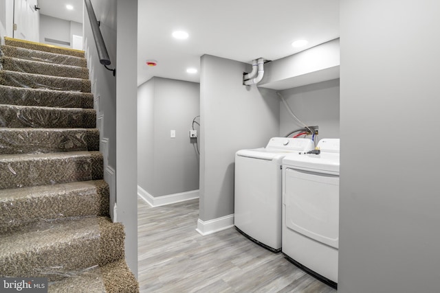 laundry area featuring washer and dryer and light hardwood / wood-style flooring