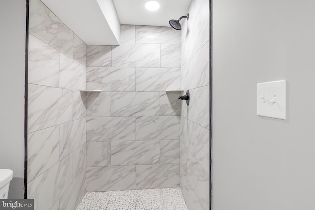 bathroom featuring a tile shower and toilet