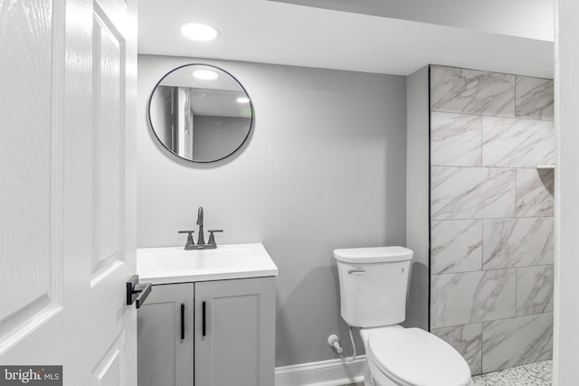 bathroom with vanity, toilet, and a tile shower