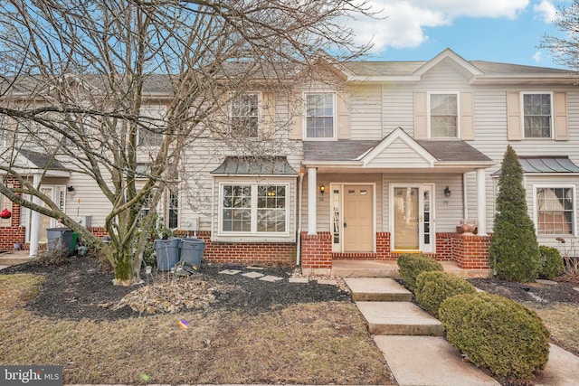 townhome / multi-family property featuring brick siding and roof with shingles