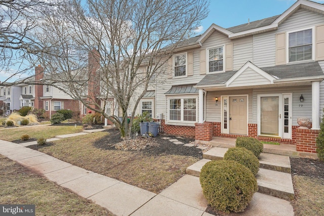 multi unit property featuring brick siding, a front lawn, and a shingled roof