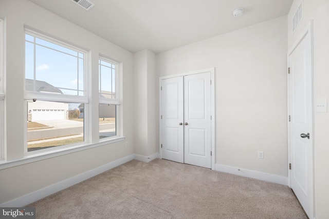 unfurnished bedroom featuring light carpet and a closet