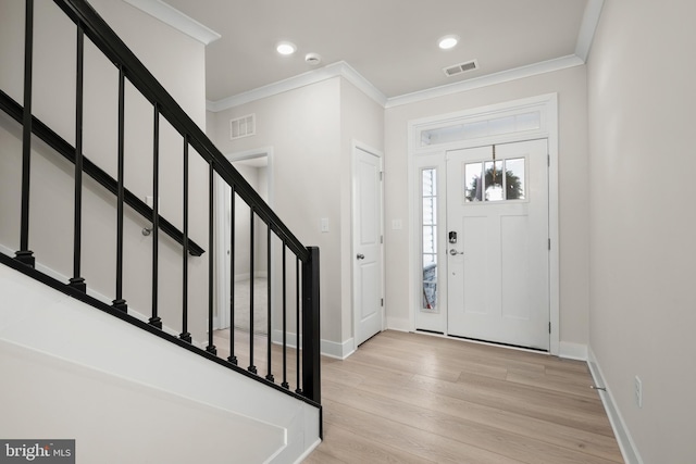 entrance foyer with ornamental molding and light hardwood / wood-style floors