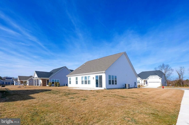 back of property with a garage, a lawn, and central AC