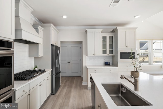 kitchen with white cabinetry, stainless steel appliances, sink, and backsplash