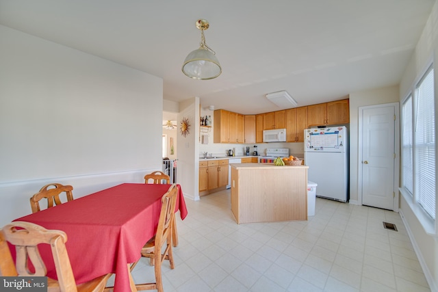 kitchen with a center island, sink, white appliances, and decorative light fixtures