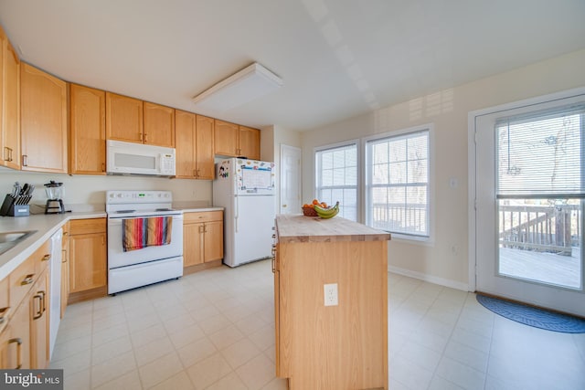 kitchen with a wealth of natural light, a center island, light brown cabinets, and white appliances